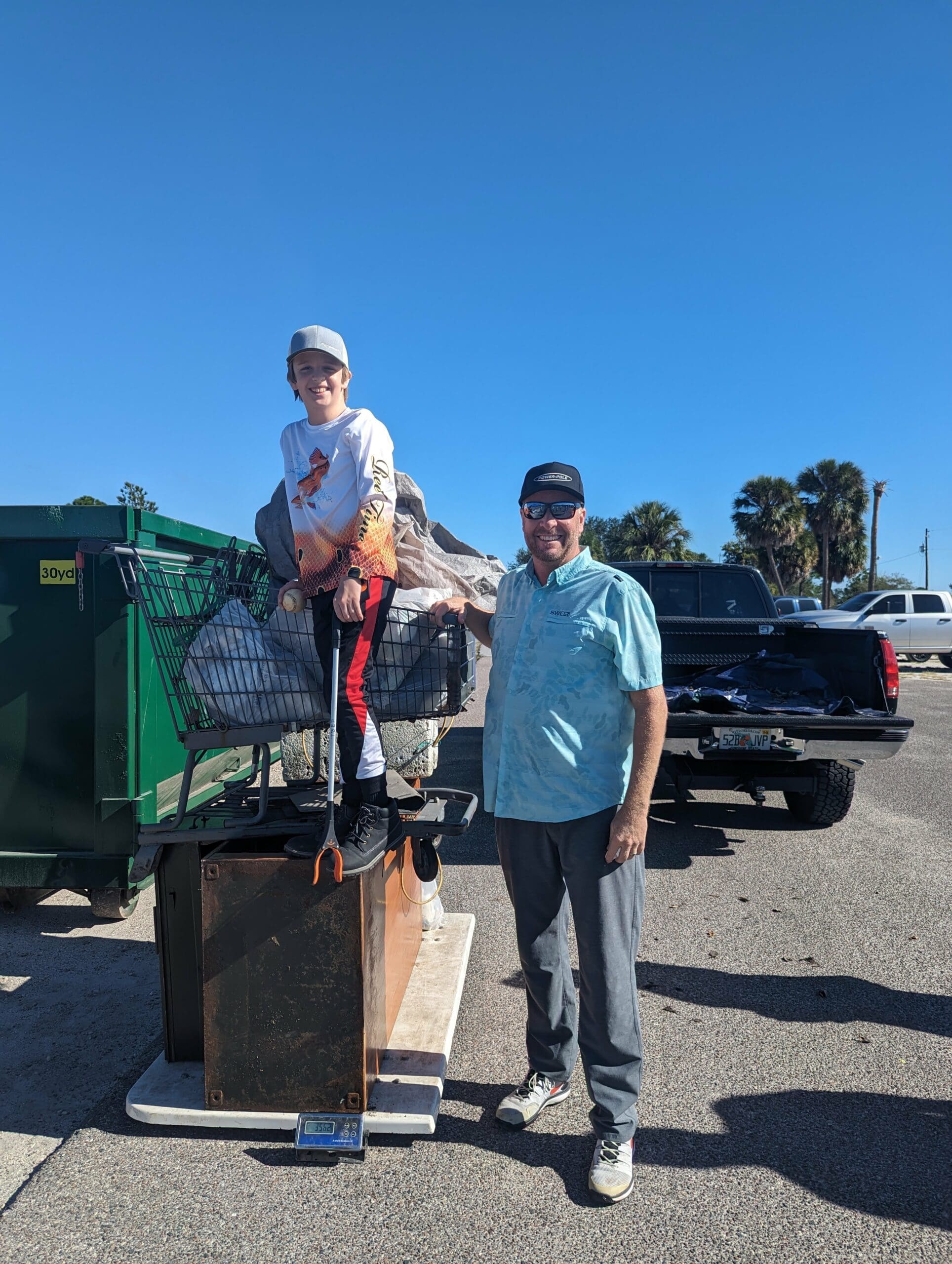 A man stands next to a young boy who is standing on a pile of trash.